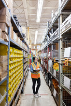 Worker With Hot Drink Looking At Stocks In Distribution Warehouse