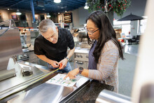 Worker And Customer Looking At Sketch Plan In Barbeque Store