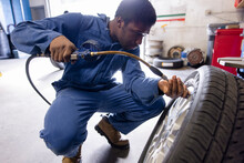 Mechanic Plugging Pressure Gauge Into Tire In Workshop