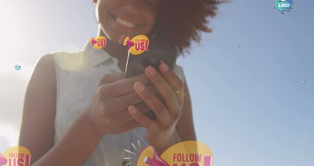 Sticker - Animation of follow us over midsection of happy biracial woman using smartphone outdoors