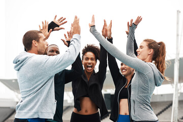 Lets go team. Cropped shot of a diverse group of athletes standing and giving each other a high five after a track session.