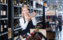 Fine Mature Female Vintner Proposing Degustation Of Wine In Modern Wine Shop