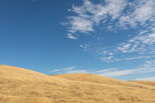 rolling hills with golden grass under blue sky