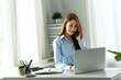 © PaeGAG - Asian businesswoman in formal suit in office happy and cheerful during using smartphone and working