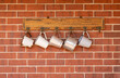 © Austockphoto - white and silver tin mugs hanging on red brick wall