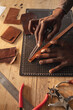 © Wavebreak Media - African american young craftsman measuring leather with scratch compass on layer cutting mat
