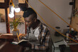 © Wavebreak Media - African american young craftsman writing on book while sitting in leather workshop