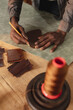 © Wavebreak Media - Midsection of african american young craftsman outlining on leather with pencil while making wallet