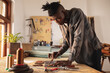 © Wavebreak Media - African american young craftsman measuring leather with scratch compass on cutting mat at workbench