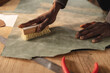 © Wavebreak Media - Cropped hands of african american young craftsman brushing leather on workbench