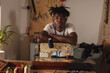 © Wavebreak Media - Portrait of african american young craftsman with arms crossed on sewing machine in leather workshop
