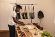 © Wavebreak Media - Side view african american young male owner arranging leather wallets on table in small store