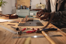 Midsection Of African American Young Craftsman Fixing Buckle On Leather Belt In Leather Workshop