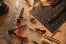 High Angle View Of Various Leather Tools With Cutting Mat On Wooden Table In Workshop