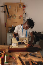 African American Young Craftsman Stitching Leather On Sewing Machine While Working In Workshop
