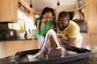 © Wavebreak Media - Amazed african american girl with father examining scientific experiment in kitchen at home