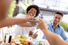 Happy Multiracial Men And Women Toasting Drinks While Sitting Together For Lunch At Table