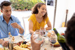© Wavebreak Media - Smiling biracial man and woman enjoying lunch together with friend at dining table