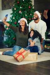 Sticker - Happy family memories warm those cold December days. Shot of a happy young family taking selfies while opening Christmas presents at home.