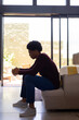 © Wavebreak Media - Side view of thoughtful african american young man with hands clasped sitting on sofa at home