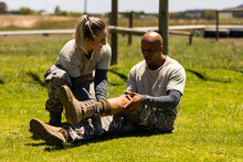 Female Caucasian Soldier Helping Injured Male African American Soldier At Boot Camp