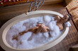 © Wavebreak Media - High angle view of sensual biracial young woman relaxing in soapy bathtub in spa