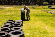 Male Soldier Rolling A Tire During Obstacle Course At Boot Camp