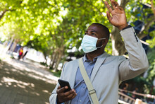 African American Businessman Wearing A Face Mask Hailing A Taxi On The Street On The Go To Office