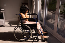 Depressed African American Disabled Woman Sitting On Wheelchair With Hands On Her Face At Home
