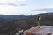 © Wavebreak Media - Full length side view of young male caucasian hiker cheering successful from mountain top