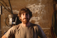 Portrait Of Bearded Caucasian Blacksmith In T-shirt Standing In Metal Industry