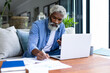 © Wavebreak Media - Confident african american senior male freelancer working with laptop and smartphone