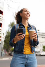 Happy African American Woman Holding Disposable Cup And Smartphone In City