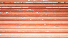 Background Color Peeling Corrugated Door. Front View Of Faded Orange Corrugated Metal Sheet Texture For Background With Copy Space. Selective Focus