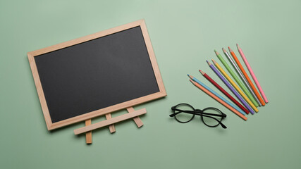 Flat lay chalkboard, glasses and stationery on green background. Back to school concept.