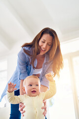 Poster - Taking his first steps. Shot of a baby learning to walk with the help of his mother.