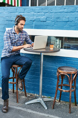 Poster - Staying entertained at the cafe. Shot of a handsome young man sitting at a sidewalk cafe.