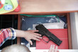 Child takes a pistol in a drawer of a nightstand