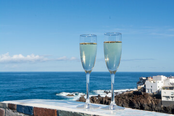 Wall Mural - New year celebration with two glasses of champagne or Spanish cava sparkling wine and view on blue Atlantic ocean, Canary islands, winter tourists destination