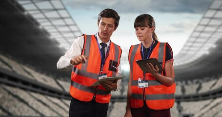 Poster - Animation of stadium over caucasian male and female workers talking and using tablet