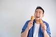 © Mallika - Happy Asian man holding fried chicken bucket standing over white background with copy space.