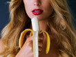 Because who doesnt like a tasty banana now and then. Cropped studio shot of a young woman eating a banana suggestively against a dark background.