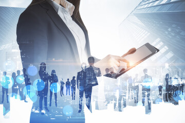 Poster - Businesswoman using pad with abstract crowd of businesspeople standing on abstract bright city background. Teamwork and success concept. Double exposure.