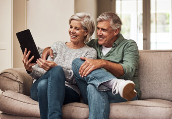 Poster - We dont know a television anymore. Cropped shot of a cheerful senior couple browsing on a digital tablet together while being seated on a couch at home during the day.
