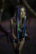 © OLEKSANDR - cute amazon woman in a fur medieval costume, in war paint, in an old forest with a spear.