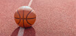 Basketball banner.Old orange ball for basketball lying on the rubber sport court.Sport red ground outdoor.Top view,Copy space.Panoramic view.