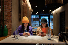 Women Browsing Smartphones In Restaurant