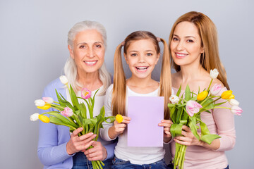 Wall Mural - Portrait of three positive peaceful woman hold bunch flowers gift card isolated on grey color background