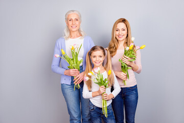 Canvas Print - Portrait of three positive idyllic woman hold bunch flowers toothy smile isolated on grey color background