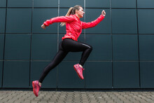 Young Woman Runner Doing Sports On Sidewalk On Modern Background. Female Model In Sportswear Exercising Outdoors. Health Concept, Take Care Of Yourself And Your Balance. Running Outdoor.
